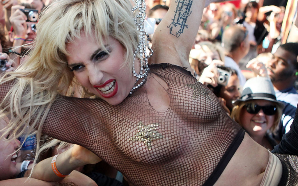 Lady Gaga crowd surfing in a fishnet top wearing gold star pasties 