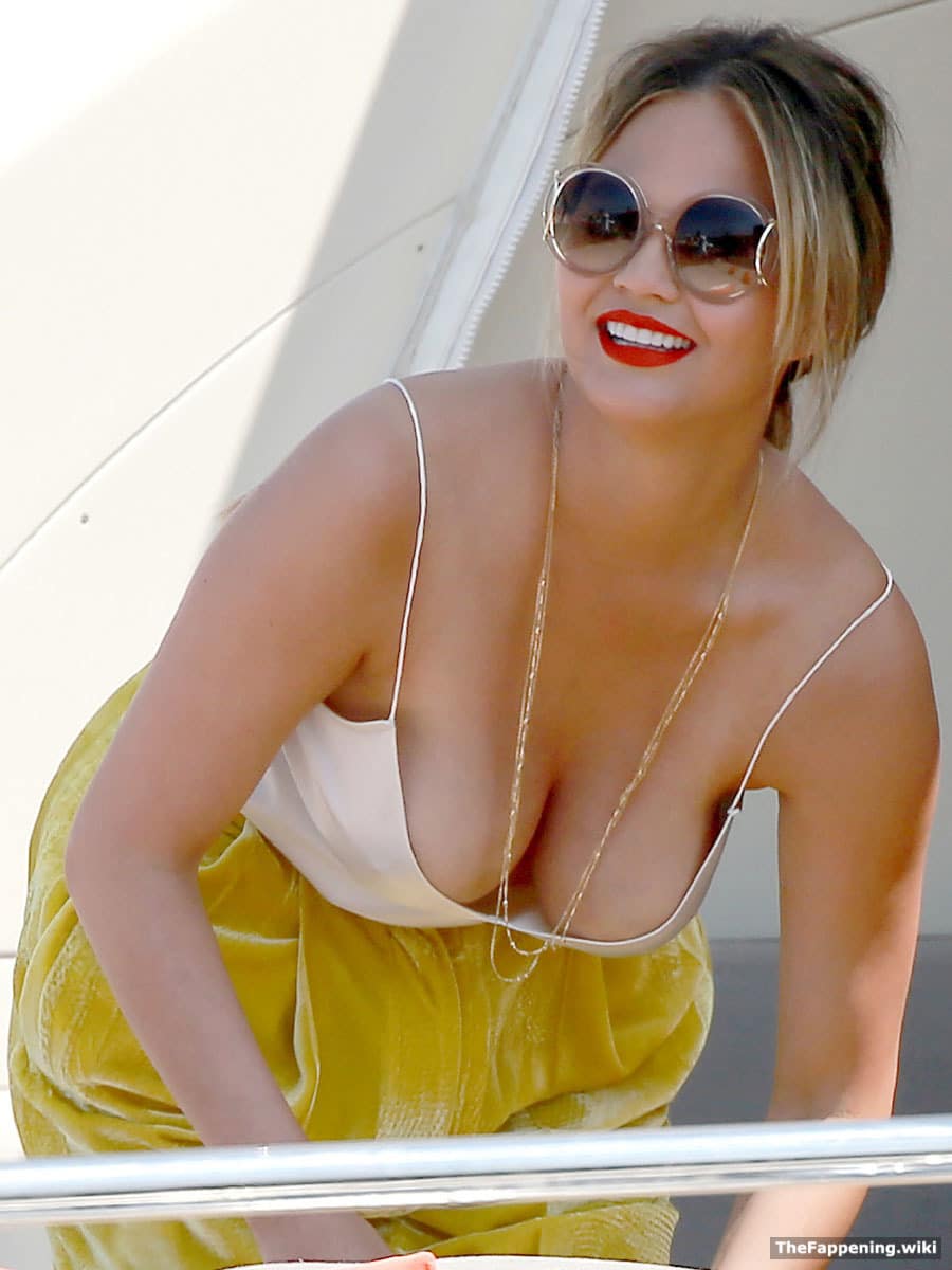 Chrissy Teigen showing her cleavage in white top and wearing sunglasses