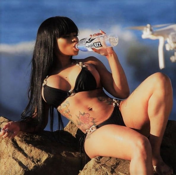 bikini modeling photo of Blac Chyna in black bikini drinking water on a rock