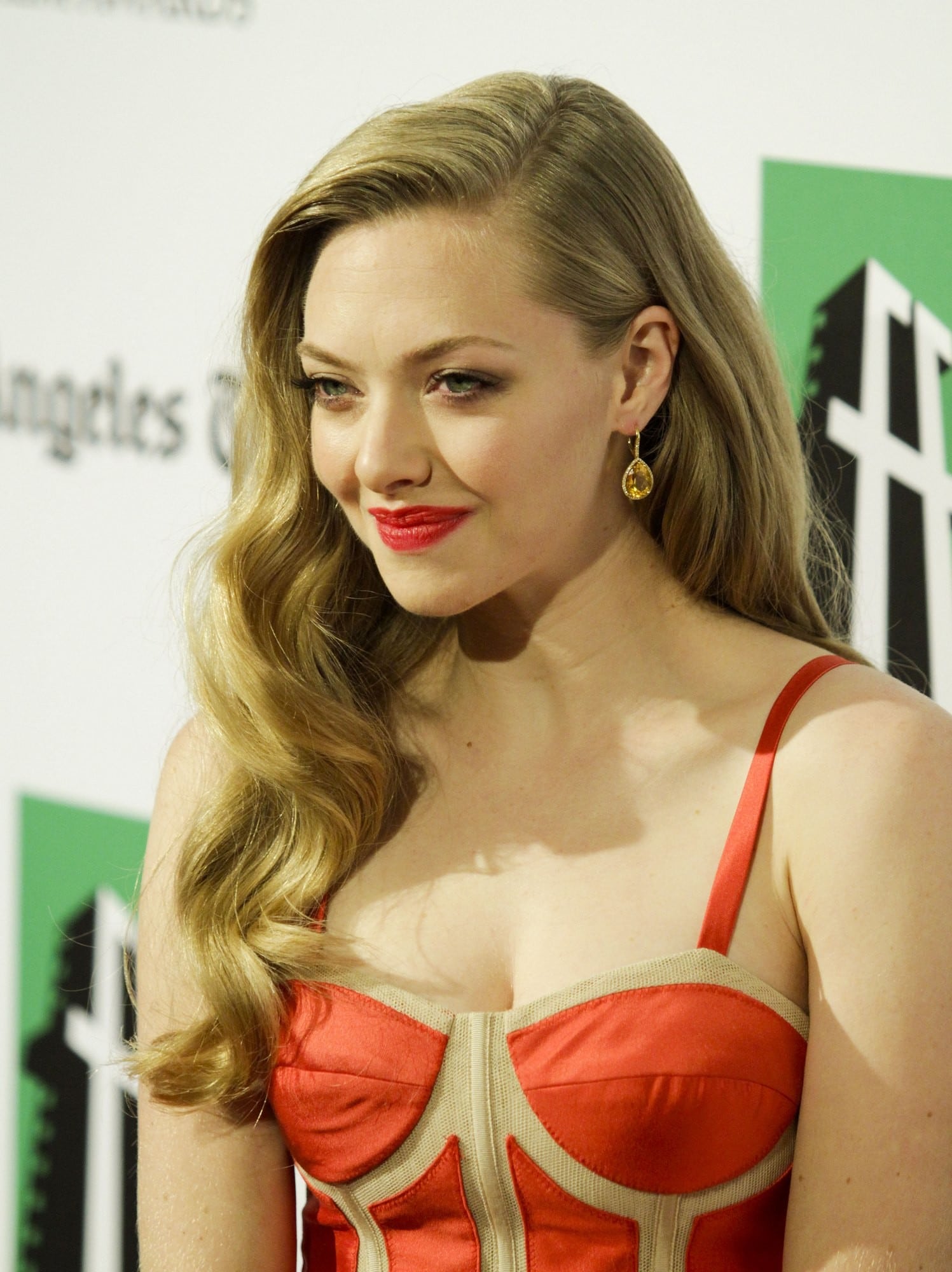 gorgeous pic of amanda seyfried on the red carpet wearing orange red dress and smiling at the camera