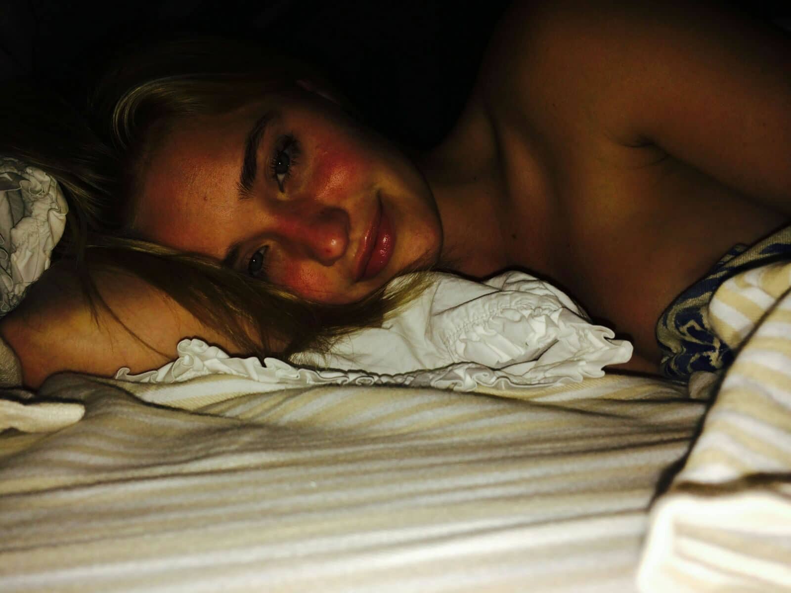 AJ Michalka laying in bed topless on her side