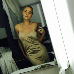 AJ Michalka taking a selfie in a gold slip dress