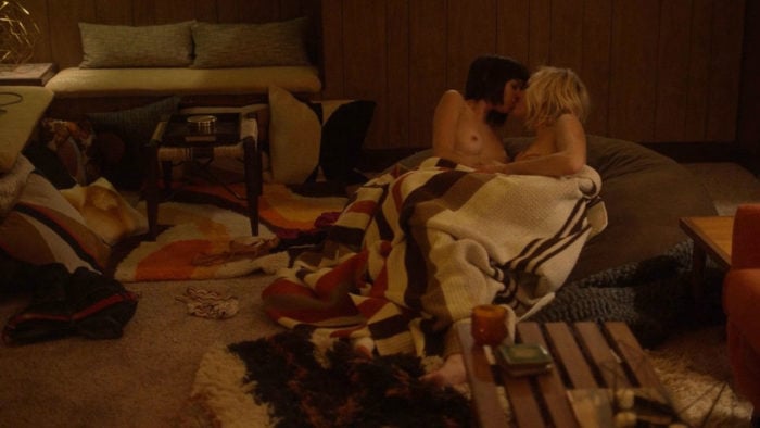 Kate Micucci making out with woman on a couch under a blanket