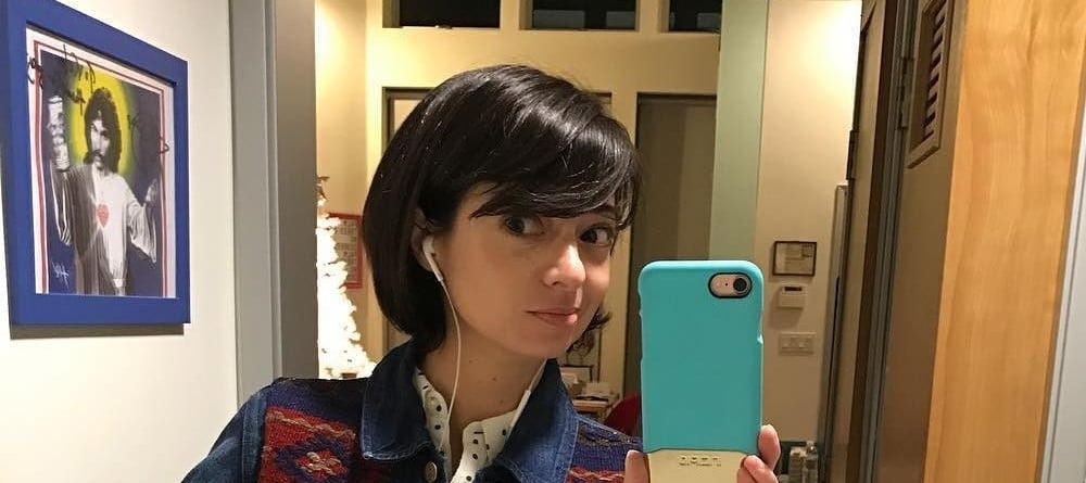 Kate Micucci taking a bathroom selfie in a jean jacket