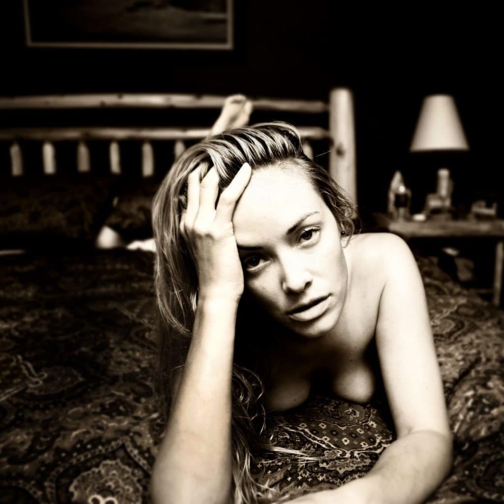 Kristanna Loken laying on bed topless with hand on head