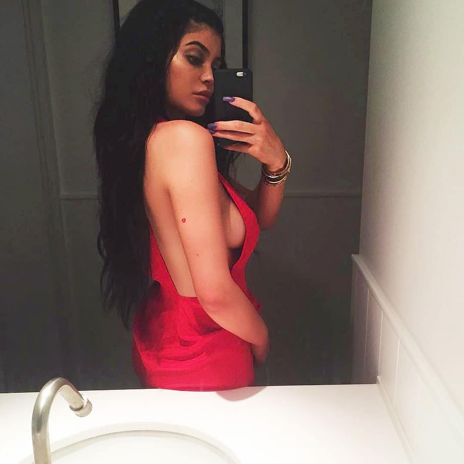Kylie Jenner taking a bathroom selfie in red dress showing some side boob
