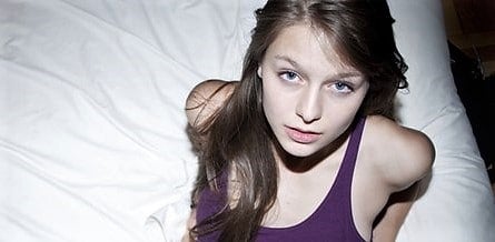 Melissa Benoist in a purple dress sitting on bed