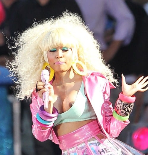 Nicki Minaj singing on stage with blond hair as nipple slips out of top