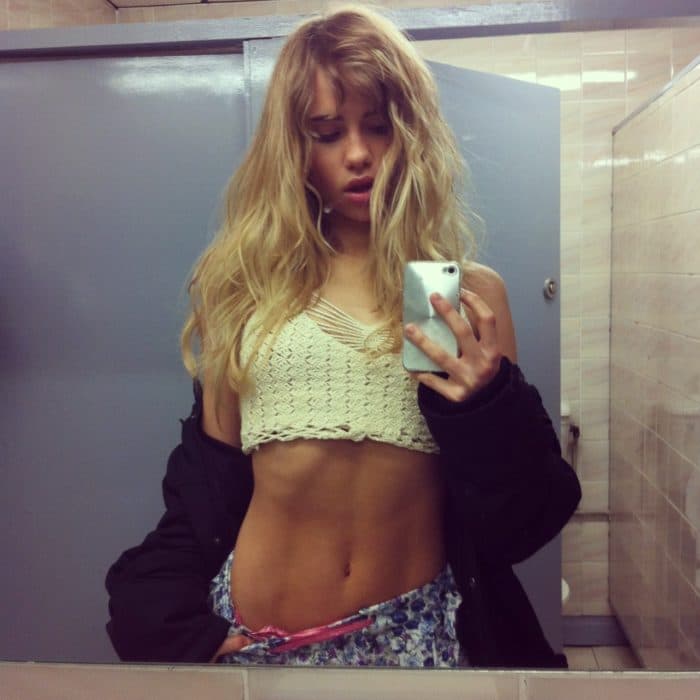 Suki Waterhouse taking a bathroom selfie in a crop top showing her abs