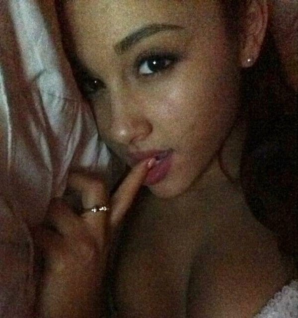 Ariana Grande laying in bed with finger in her mouth