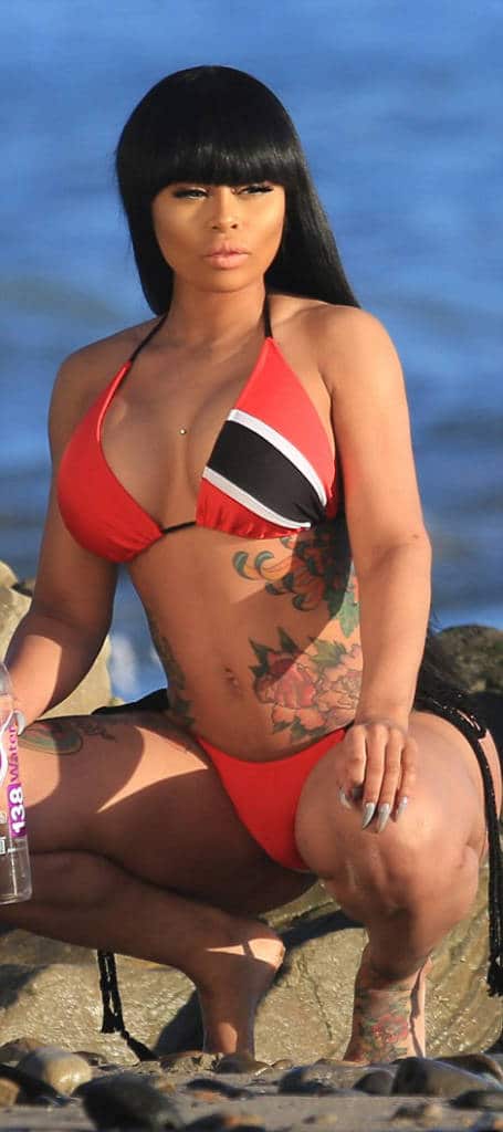 Blac Chyna in a red and blue swimsuit squatting