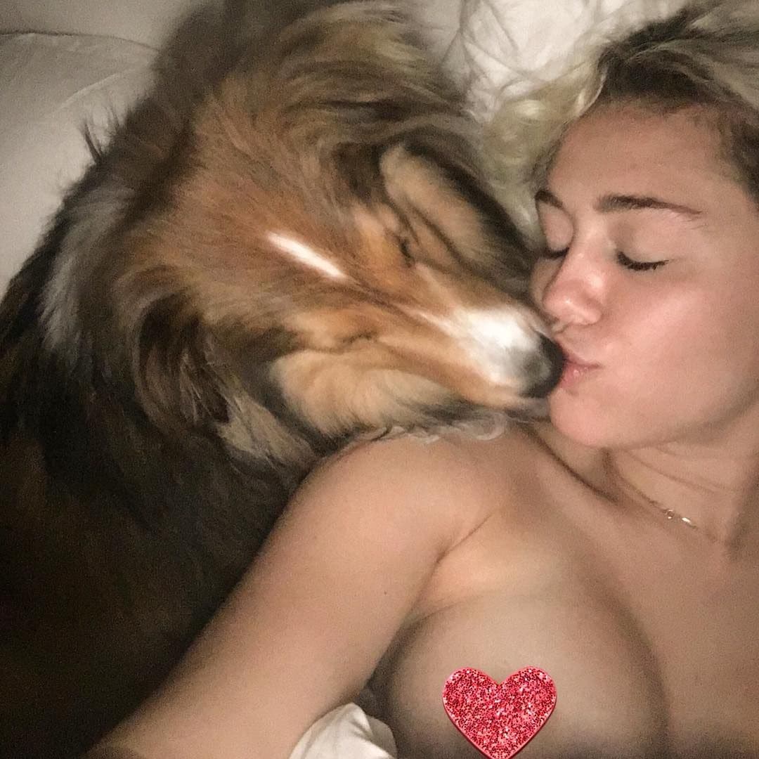 Miley Cyrus kissing her dog with pasties on her nipples