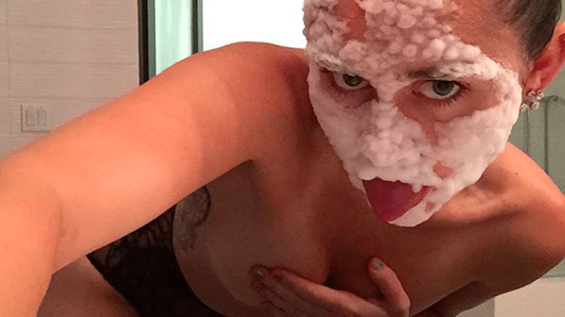 Miley Cyrus with cream on her face covering tit with hand
