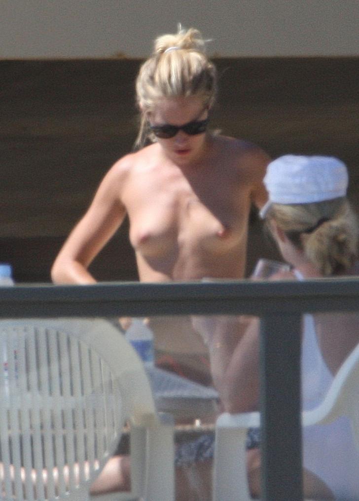 Sienna Miller with sunglasses on and showing her boobs on a balcony