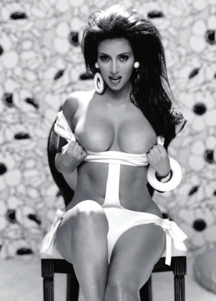 Kim Kardashian in black and white photo pulling her top down and showing off her big boobs