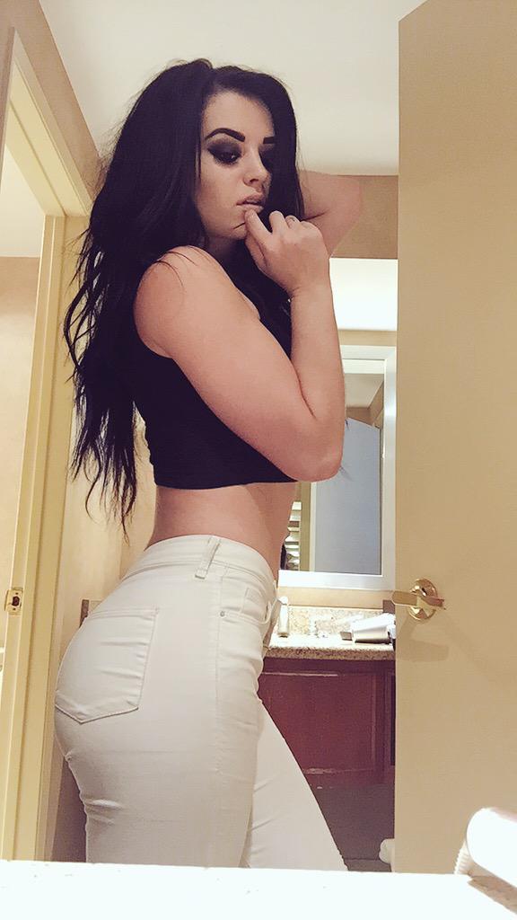 Paige in white pants and black top sticking her ass out